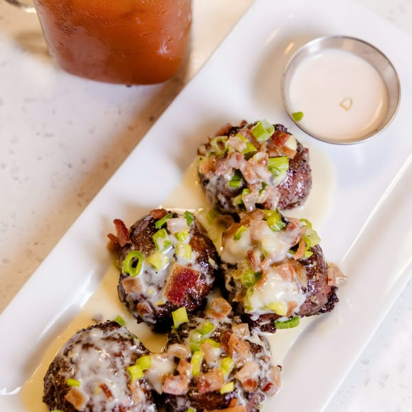 Savory brunch bites with bacon, green onions, and creamy sauce, served with a side of dipping sauce.